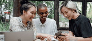 three women looking at something on a mobile phone and laughing
