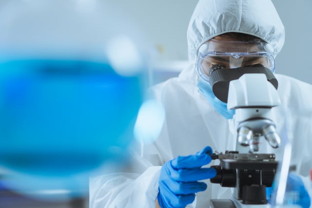 image shows a female student looking through a microscope