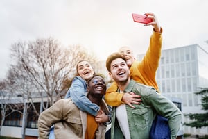 image shows four students taking a picture on their phone on campus