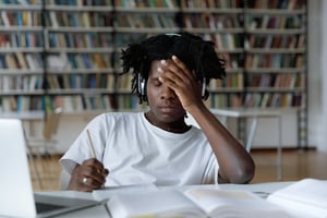 image shows a student with his head in his hands