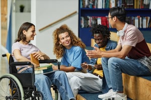 image shows a group of students talking, and one student is a wheelchair user