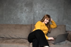 image shows a female student sitting on a sofa