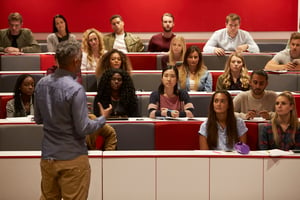 image shows a professor standing in front of a lecture hall 