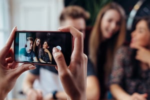 image shows someone using their mobile phone to film three people in the background 