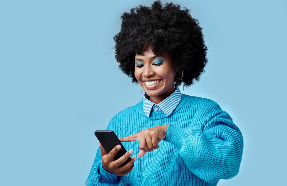 image shows a woman smiling scrolling on her phone