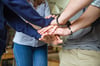 image shows people putting their hands altogether