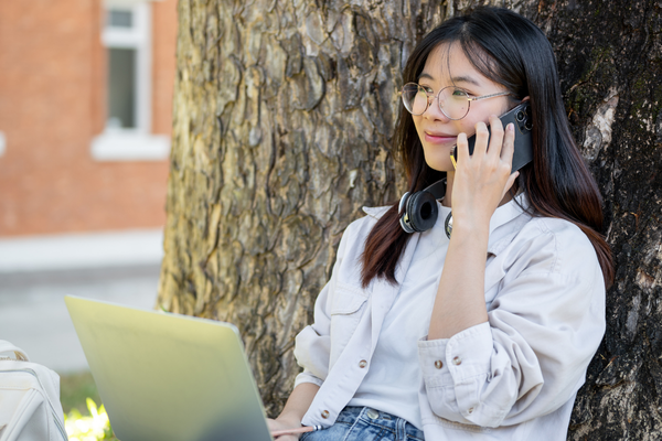 female student on cell phone with laptop