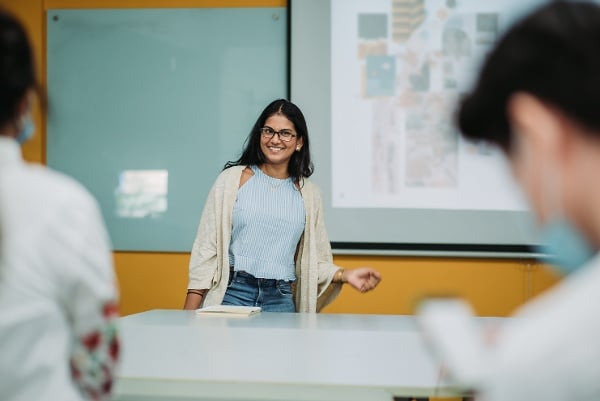 a female teacher standing in front of a presentation screen in a lecture