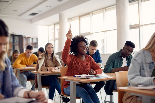 Class of students in classroom, with one student raising their hand