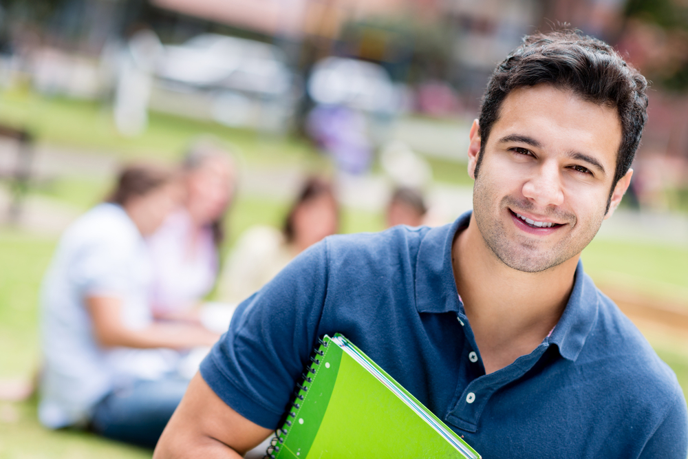 Happy male student holding a notebook and smiling