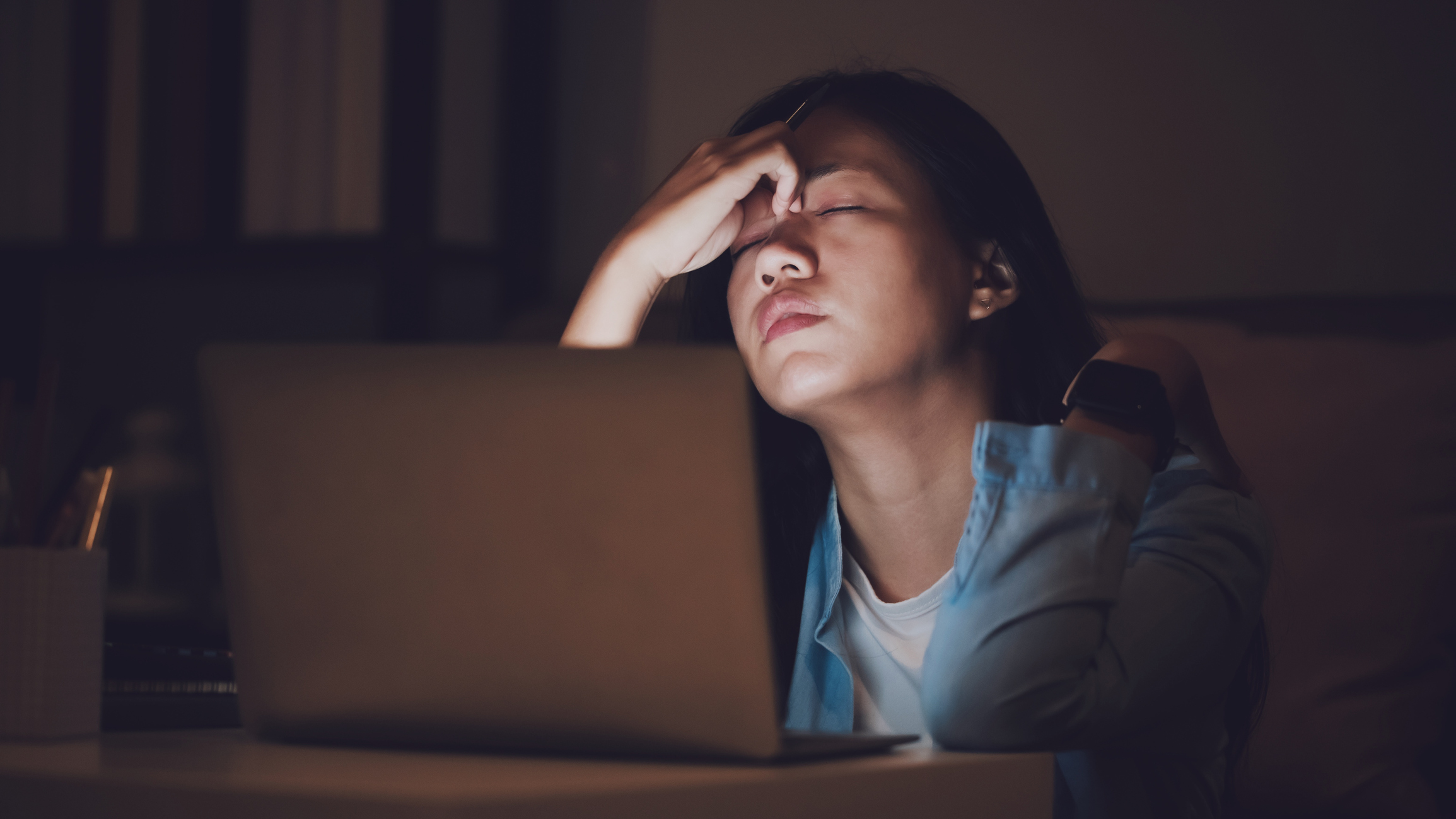 Photo of student at a laptop holding her head and looking stressed