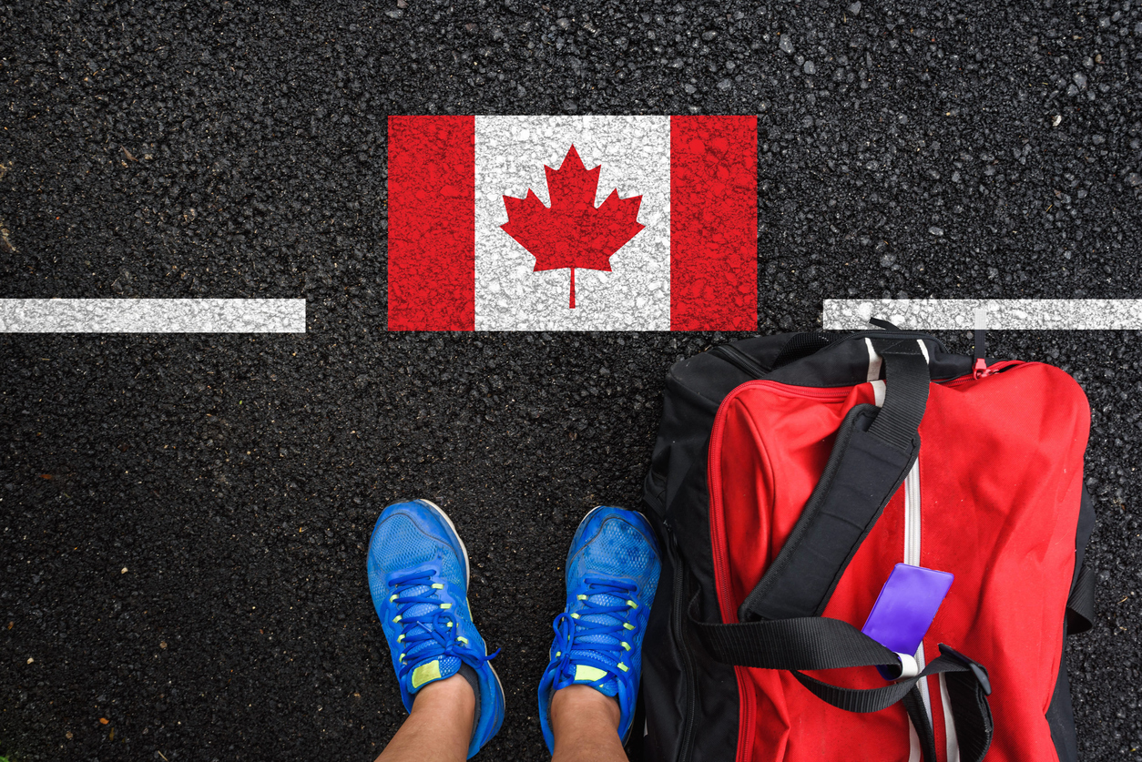 image shows someone standing beside a Canadian flag 