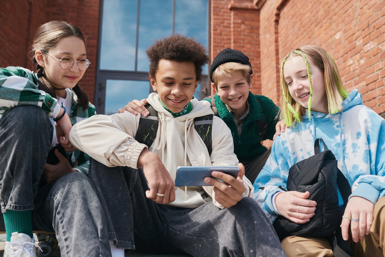 image shows a group of Generation Alpha kids all watching a smartphone