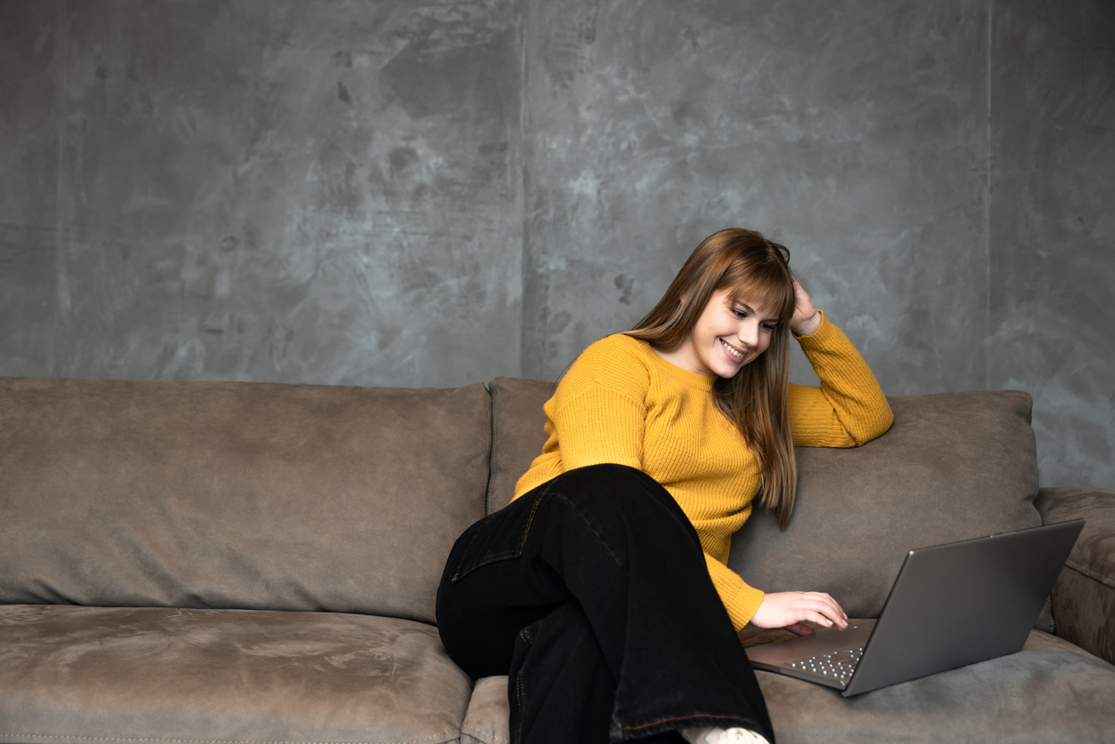 image shows a female student sitting on a sofa