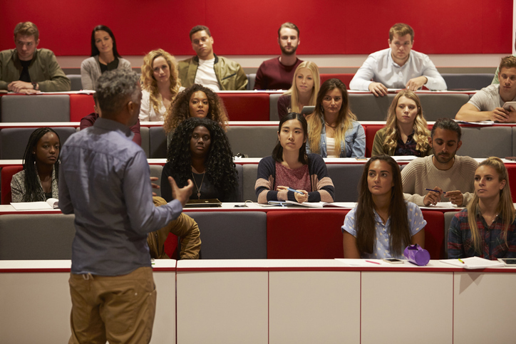 image shows a professor standing in front of a lecture hall 