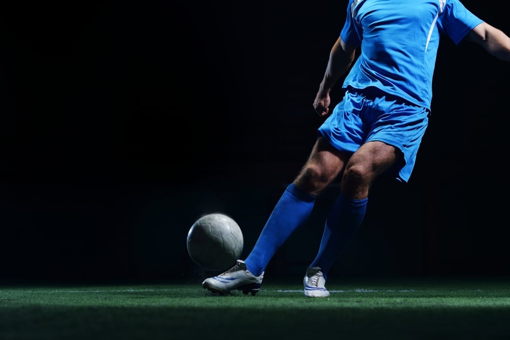 soccer player doing kick with ball on football stadium  field  isolated on black background